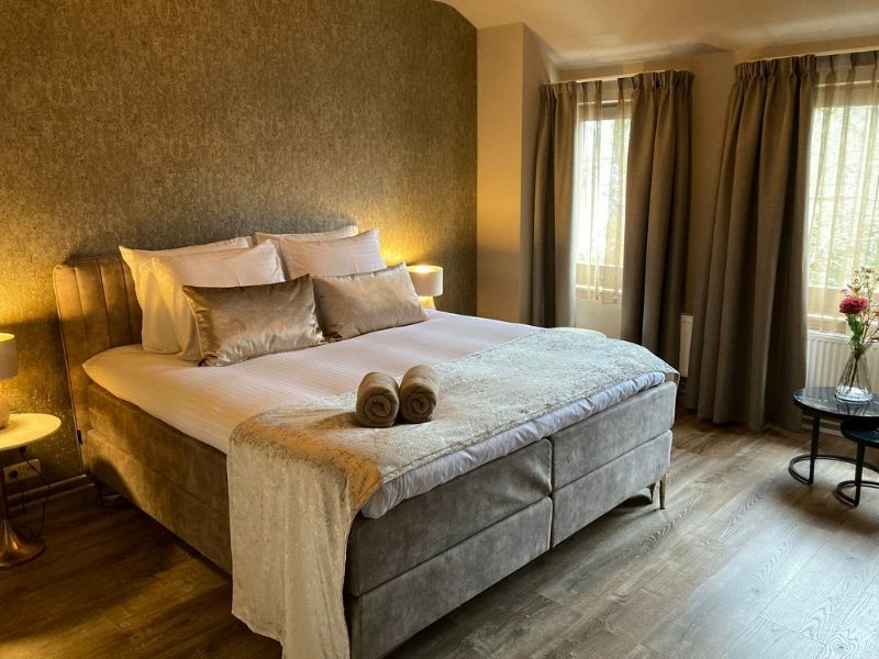 Sfeervol ingerichte hotelkamer met luxe boxspring, zachte handdoeken en natuurlijk licht bij De La Frontière Bed & Borrelbistro in Slenaken