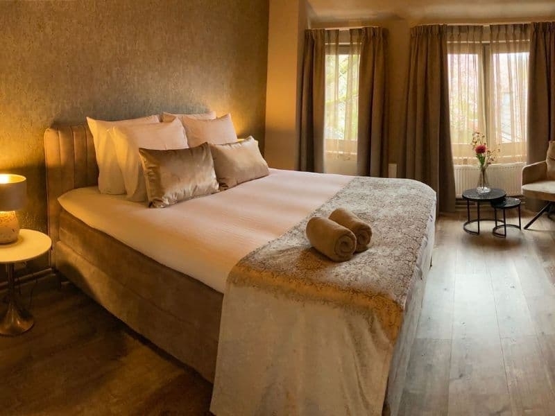 Sfeervolle hotelkamer met luxe bed en warme inrichting bij De La Frontière in Slenaken