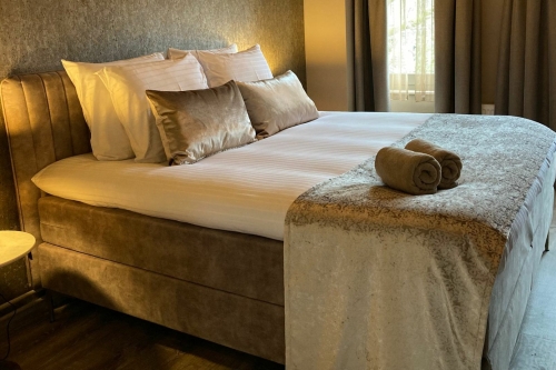 Warm ingerichte hotelkamer met luxe boxspring, sfeerverlichting en houten vloer bij De La Frontière Bed & Borrelbistro in Slenaken