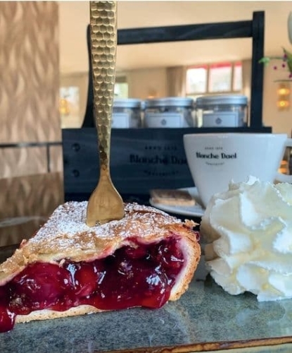 Ambachtelijke kersenvlaai van Peter Lemmens met slagroom en een kop koffie van Blanche Dael bij De La Frontière Bed & Borrelbistro in Slenaken