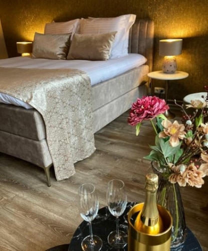 Sfeervol ingerichte hotelkamer met boxspring, champagne op ijs en bloemen bij De La Frontière Bed & Borrelbistro in Slenaken