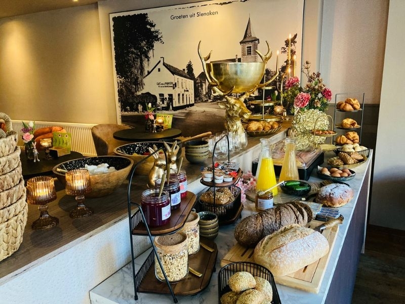Rijkelijk gedekt ontbijtbuffet met vers brood, jam, croissants en vers sap in de ontbijtruimte van De La Frontière Bed & Borrelbistro in Slenaken