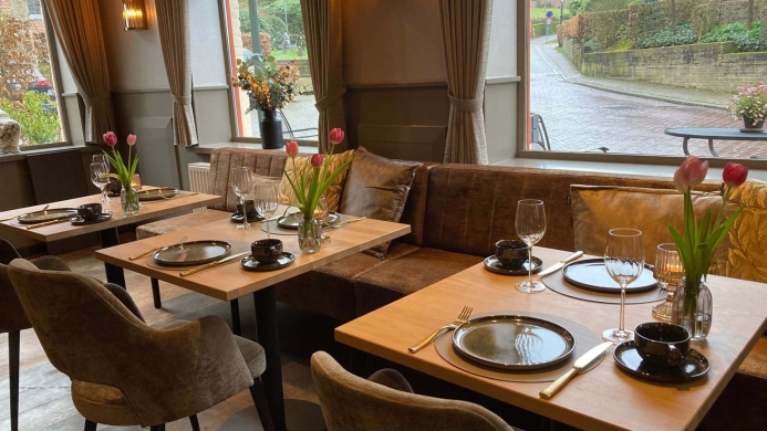 Sfeervolle gedekte tafels met tulpen en uitzicht op de straat in de borrelbistro van De La Frontière in Slenaken