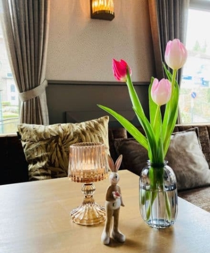 Sfeervolle zithoek met tulpen en kaarslicht in de borrelbistro van De La Frontiëre Bed & Borrelbistro in Slenaken