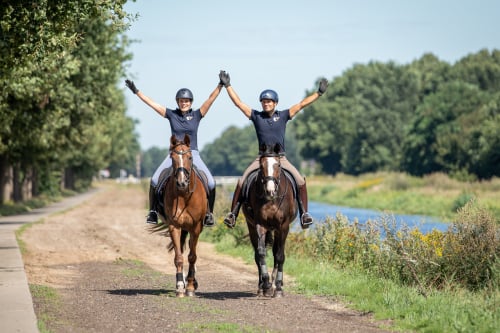 Foto van Amber Koppen en Bastiaan de Recht waar ze allebei op een paard zitten