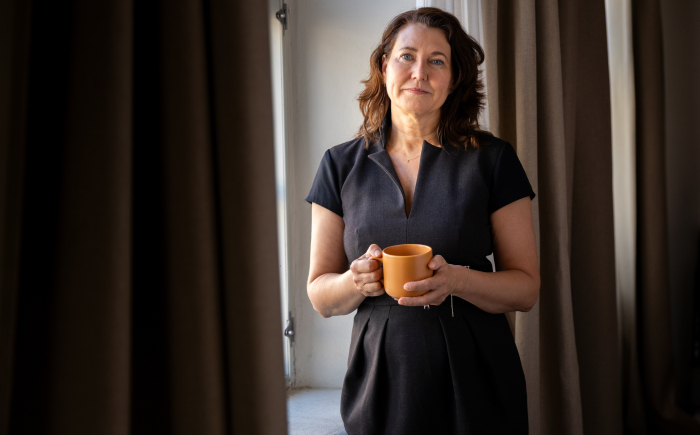 Advocaat Mediator en initiatiefneemster Sarah Köller bij een raam met een kop koffie in de hand