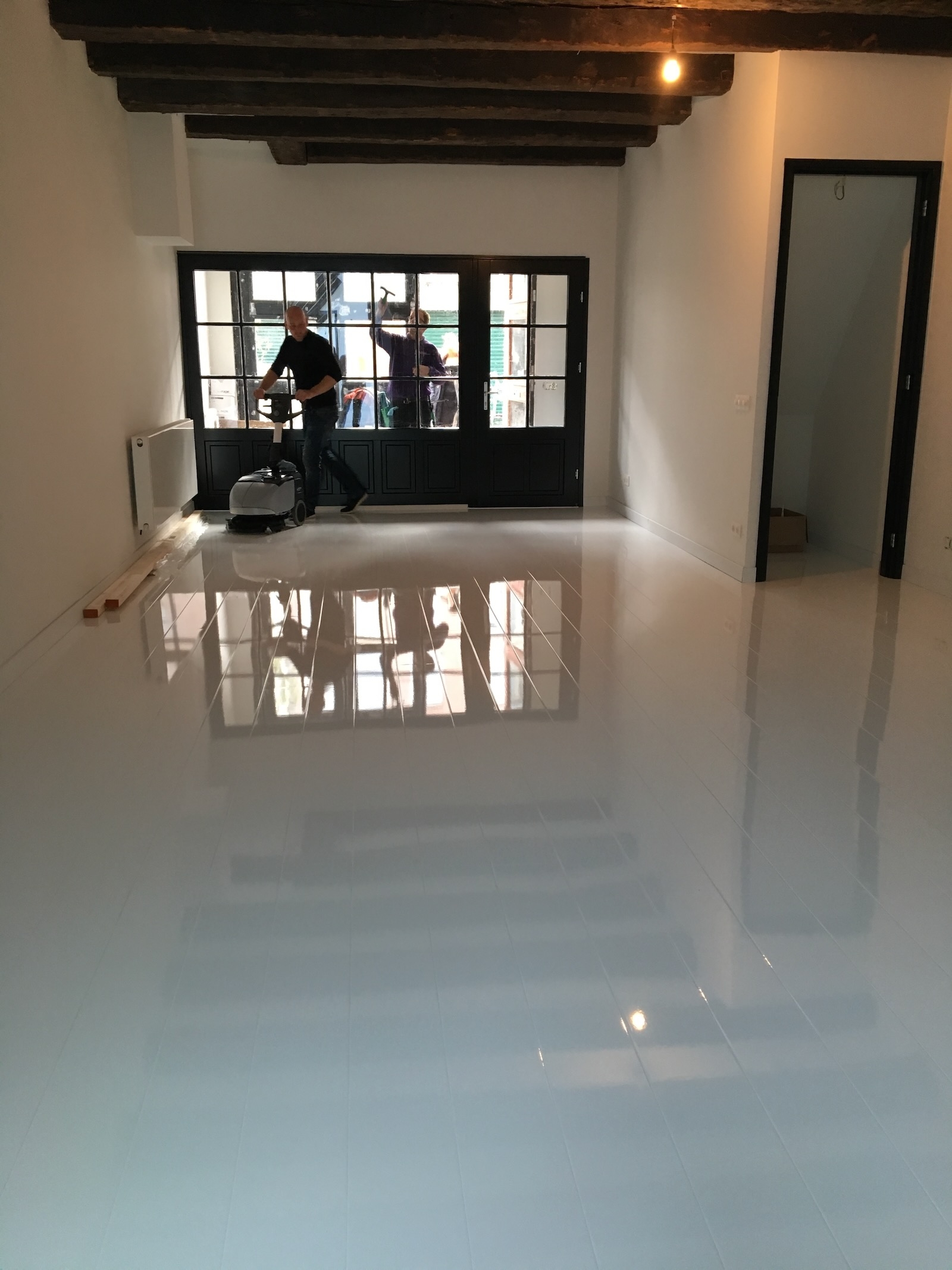 Medewerkers van De Schoonmaak reinigen een vloer en de ramen bij een oplevering