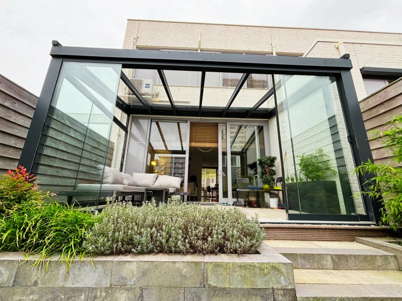 Tuinkamer antraciet met glazen schuifwanden en glasdak met geïntegreerde led-verlichting Ruime antraciet aluminium tuinkamer met glazen schuifwanden en zonwering Nesselande