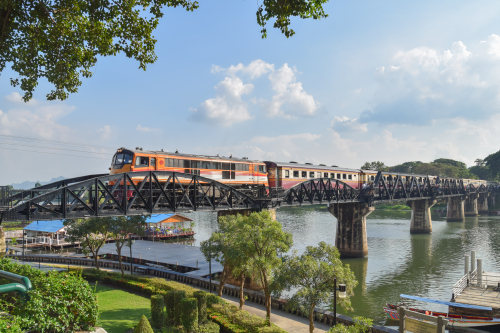 Zwarte stalen boogbrug over de River Kwai in Kanchanaburi, omgeven door groene natuur