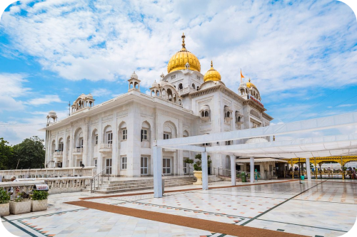 Vooraanzicht van de witmarmeren Gurdwara Bangla Sahib met gouden koepels in New Delhi.