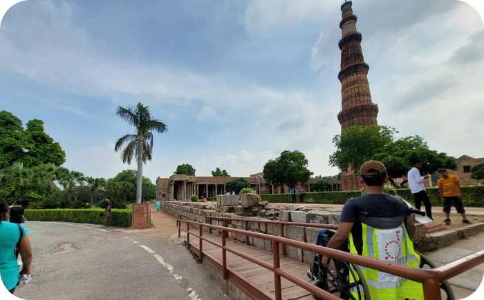 Een man in een rolstoel rijdt over een toegankelijkheidspad bij de historische Qutub Minar in New Delhi