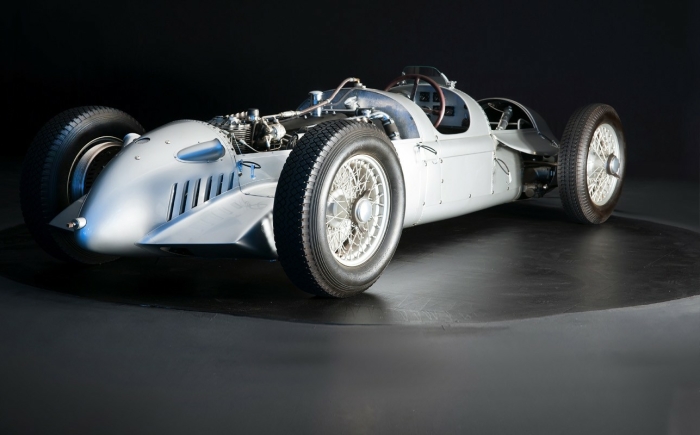 Een vintage zilveren Auto Union Type D Grand Prix-racewagen opgesteld tegen een zwarte achtergrond.