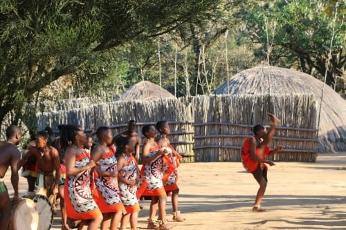 A group Mantenga Cultural Village individuals wearing colorful traditional clothing from various cultures.