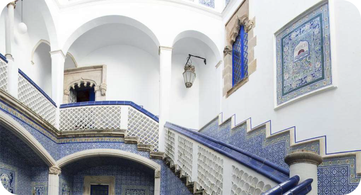 Binnenplaats van Palau de Maricel met witgekalkte muren, een stenen boog en trappen met blauw-witte keramische tegels