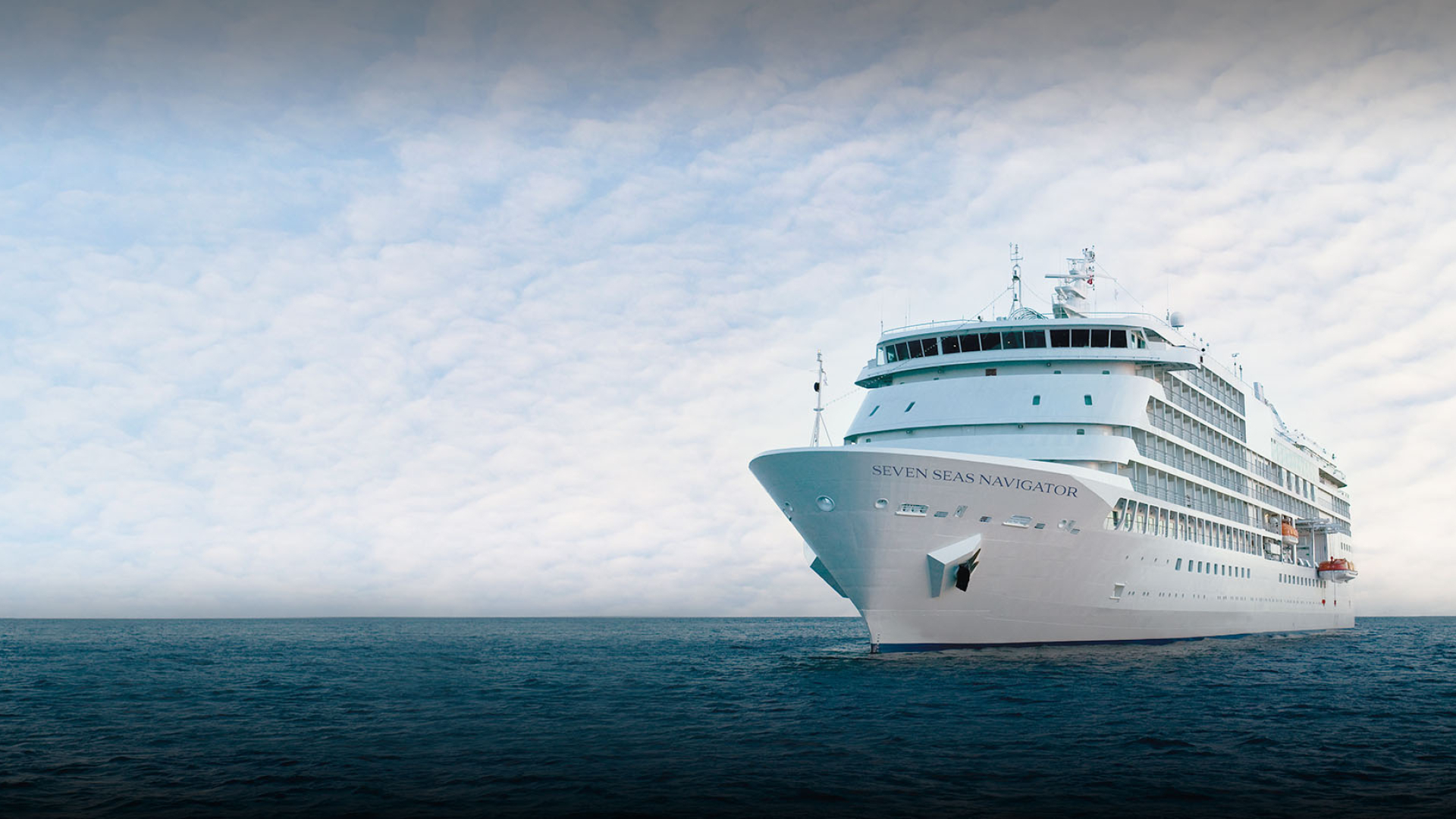 Luxe cruiseschip Seven Seas Navigator op open zee onder een bewolkte hemel, varend richting de horizon met kalm water op de voorgrond.