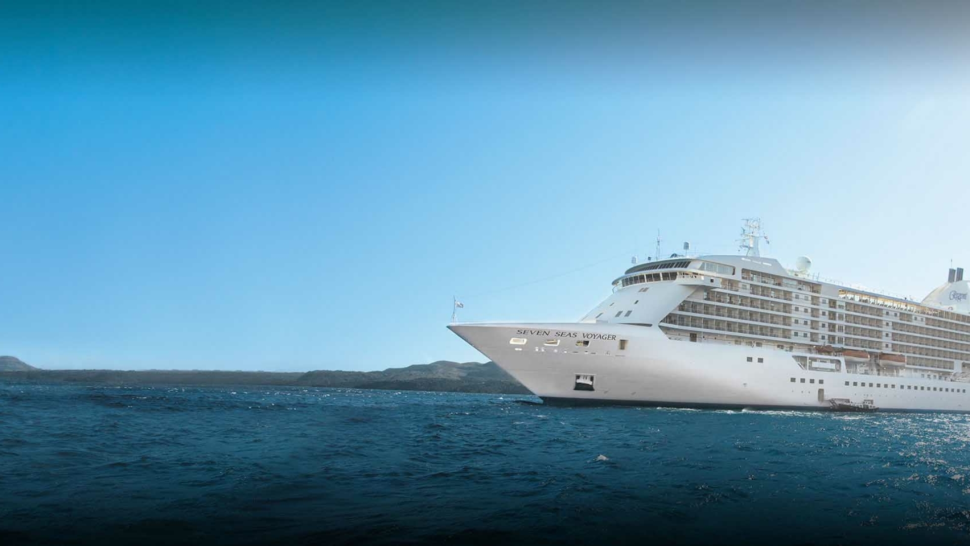 Luxe cruiseschip Seven Seas Voyager op open zee heldere hemel, varend richting de horizon met kalm water op de voorgrond.
