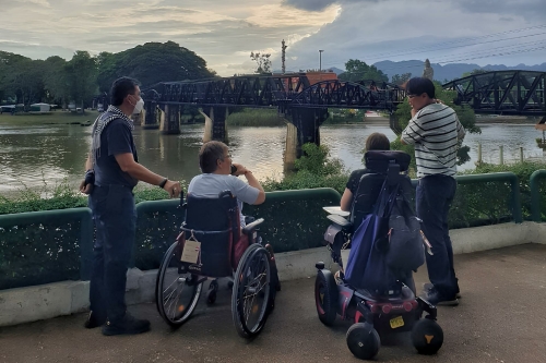 Zwarte stalen boogbrug over de River Kwai in Kanchanaburi, omgeven door groene natuur