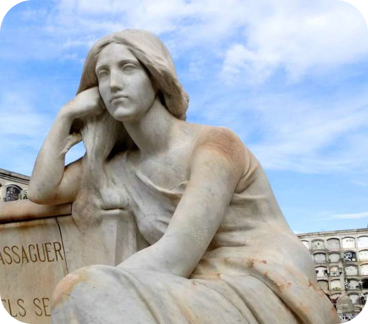 Witmarmeren standbeeld van een treurende, zittende vrouw in modernistische stijl op een historische begraafplaats onder een blauwe lucht.