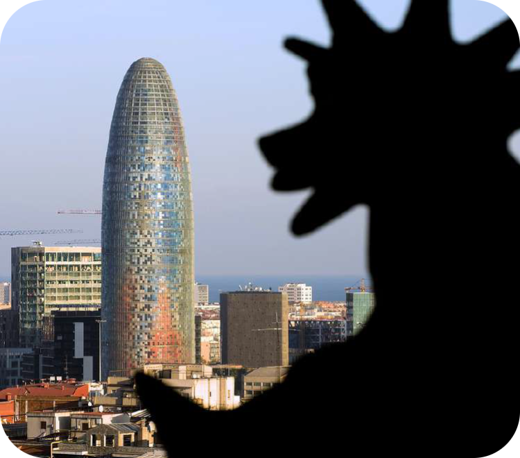 Moderne cilindervormige wolkenkrabber (Torre Glòries) met een glazen gevel in Barcelona, deels overlapt door een zwart silhouet op de voorgrond.