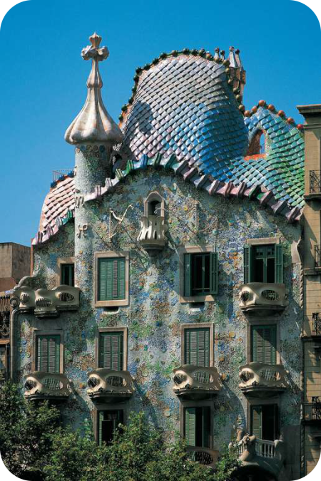 De kleurrijke, golvende gevel van Casa Batlló in Barcelona met een dak dat lijkt op een geschubde drakenrug onder een blauwe lucht.