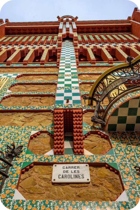 Kleurrijke mozaïekgevel van Casa Vicens in Barcelona met een straatnaambordje voor Carrer de les Carolines.