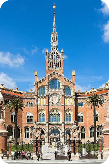 Hoofdingang van het modernistische Hospital de Sant Pau in Barcelona met een opvallende, rijk versierde klokkentoren en bakstenen gevel onder een blauwe lucht