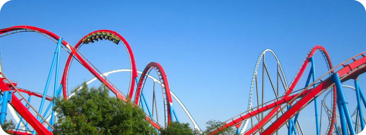 Een panorama van de kleurrijke achtbanen Dragon Khan (rood) en Shambhala (wit/blauw) in attractiepark PortAventura onder een strakblauwe lucht