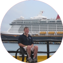 John sage zitten in zijn rolstoel op de kade voor een cruiseschip van Disney Cruises