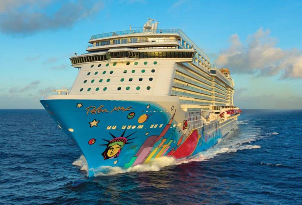 Cruiseschip Norwegian Breakaway vaart over een kalme zee onder een heldere blauwe lucht, gezien vanaf de zijkant
