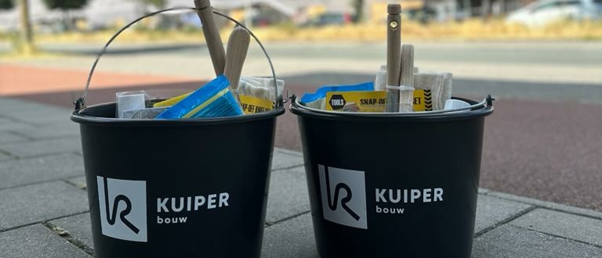 2 gevulde bouwemmers bedrukt met logo van Kuiper Bouw voor bouwlocatie