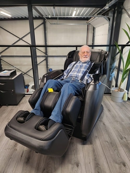 Klant geniet van luxe massagestoel bij autobedrijf