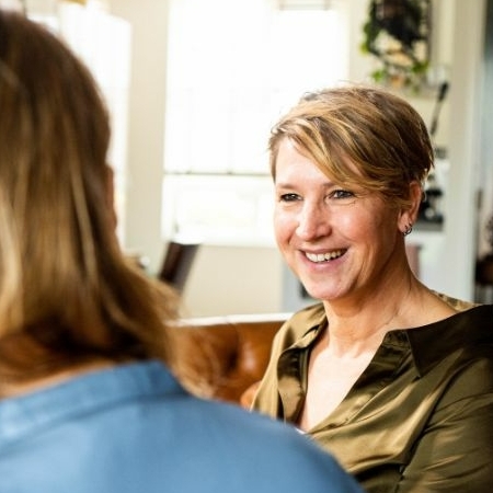 Evelyn Scholtens - van der Stok van Evolve Life Center luistert met een warme, aandachtige blik naar een cliënt tijdens een 1-op-1 coachingsessie.