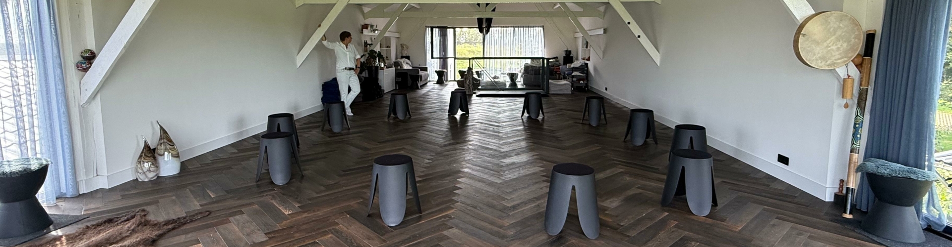 Stap in een ruimte die verandering ademt Lichte, serene workshopruimte met houten vloer, opstellingen in een kring en rustgevende sfeer in Huize Leeghwater – locatie van de Doorbraakdag van Evolve Life Center.