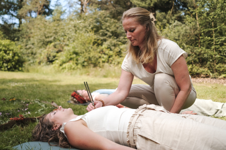 Vrouw doet met stemvork op hartchakra soundhealing