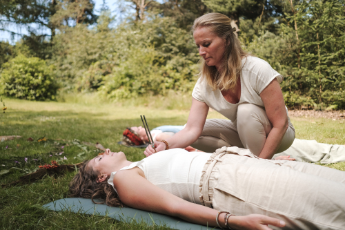 Vrouw doet met stemvork op hartchakra soundhealing