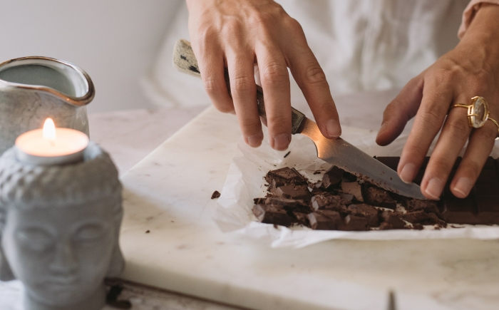 Vrouw maakt blok cacao klein met mes