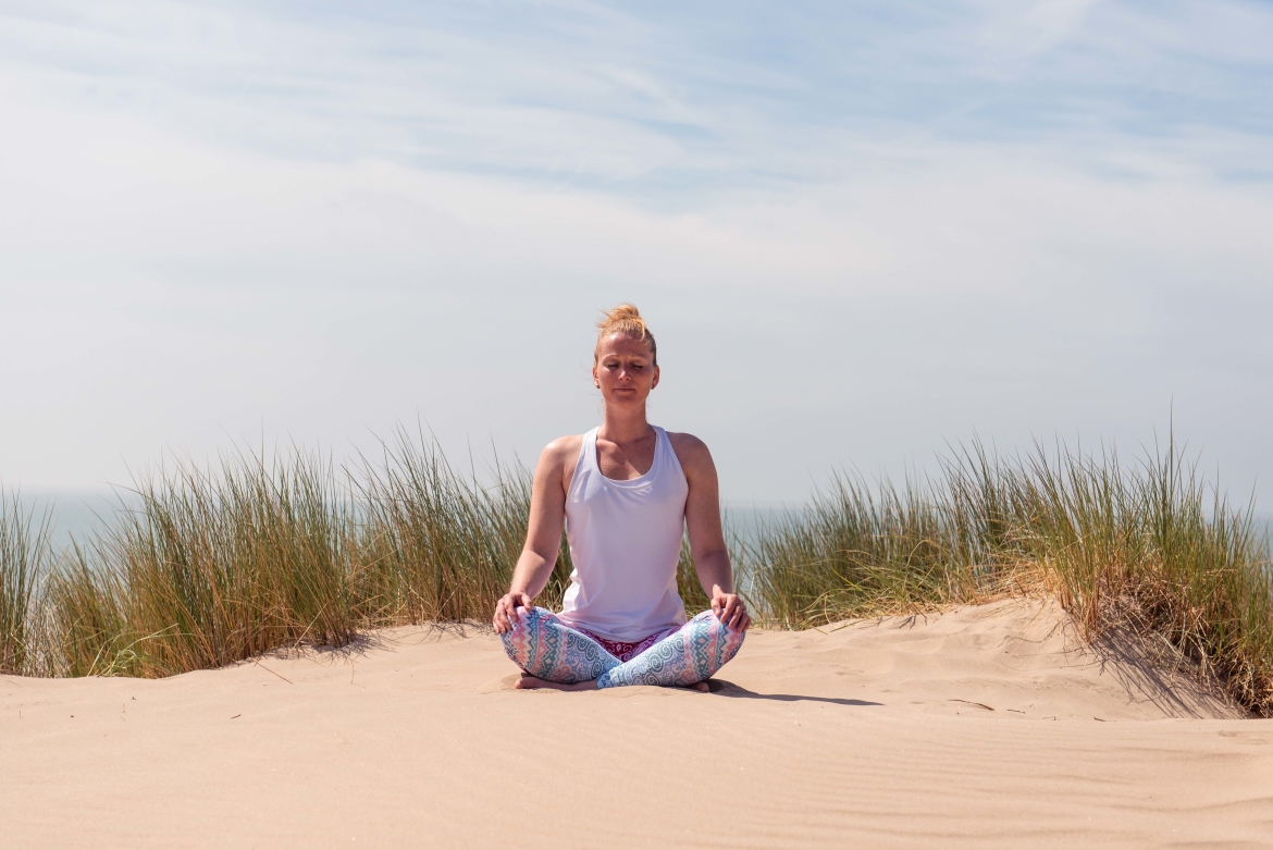 Vrouw mediteert op het strand, even stilstaan en me-time
