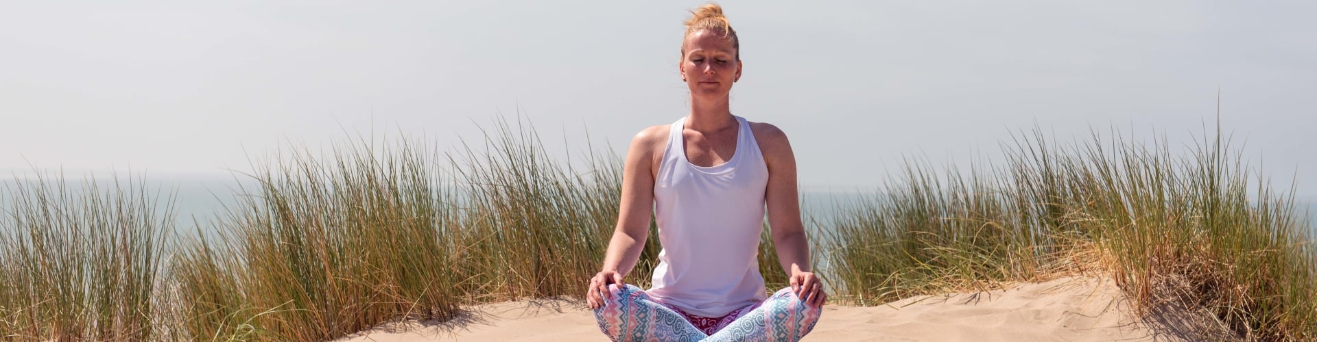 Vrouw mediteert op het strand, even stilstaan en me-time