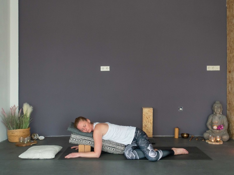Vrouw doet restorative yoga houding liggende buiktwist