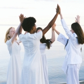 Sisterhood; 5 vrouwen in het wit houden elkaars handen vast in de lucht