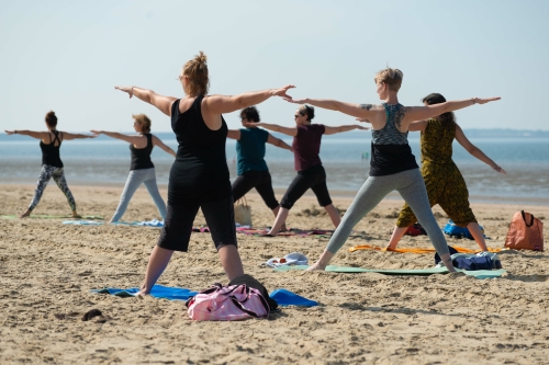 Mensen doen yoga op het strand_voorbereiding Trikonasana driehoekshouding