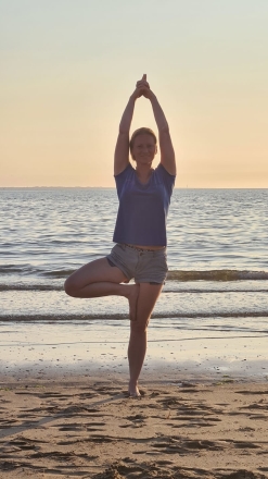 Marjolein doet yogahouding Yogahouding Trikonasana boomhouding op het strand