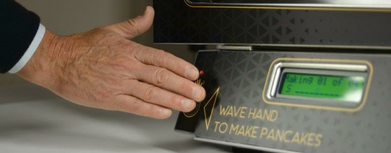 Hotelgast pakt verse pannenkoeken uit een touchless machine tijdens een stijlvol ontbijtbuffet.