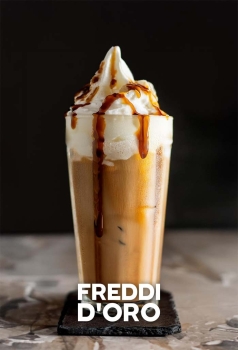 Freddi D'Oro IJskoffie in een tumblerglas met romige caramelbruine textuur, slagroom en een drizzle van caramel of chocolade.