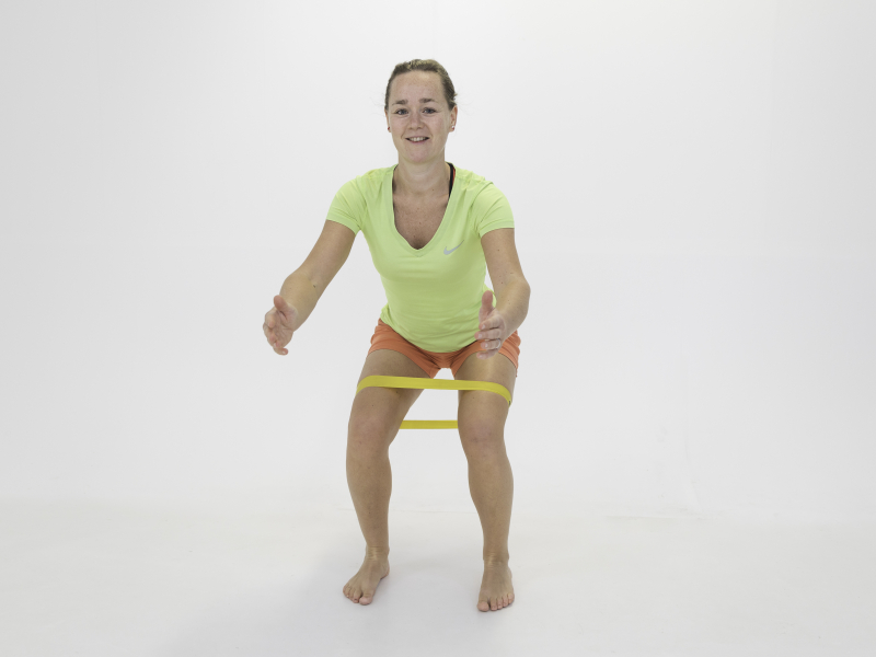 Fysio Maaike doet squat met weerstandsband