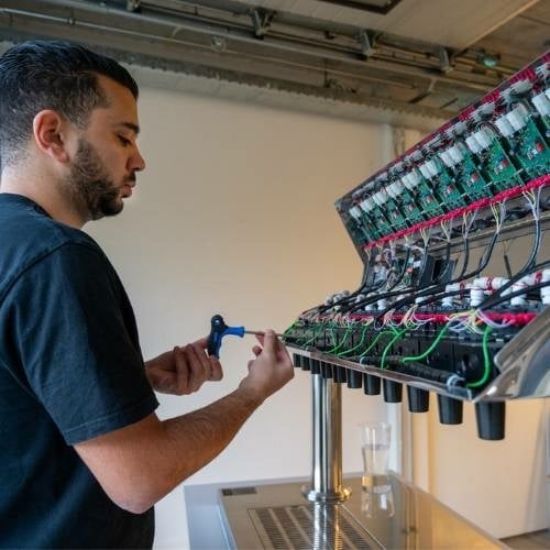 Een monteur van Grapos werkt aan een postmixmachine Een monteur van Grapos doet onderhoud aan een postmixmachine zodat hij altijd goed werkt.