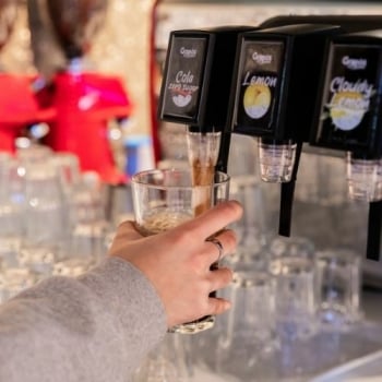 Iemand tapt een glas duurzame Grapos frisdrank ui een postmixmachine. Iemand tapt een glas duurzame Grapos frisdrank ui een postmixmachine.