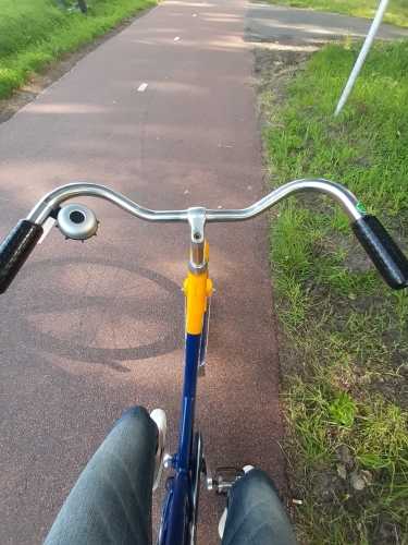 Voorkant van een fiets van bovenaf genomen terwijl iemand fietst.