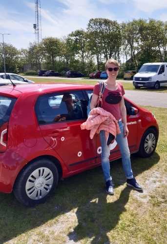 Petra bij een geparkeerde rode Greenwheels auto