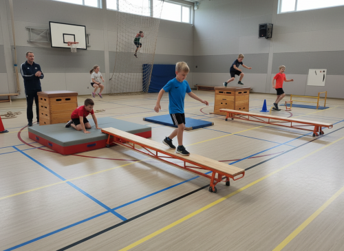 Kinderen trainen op gekleurde gymbanken in schoolgymzaal met docent